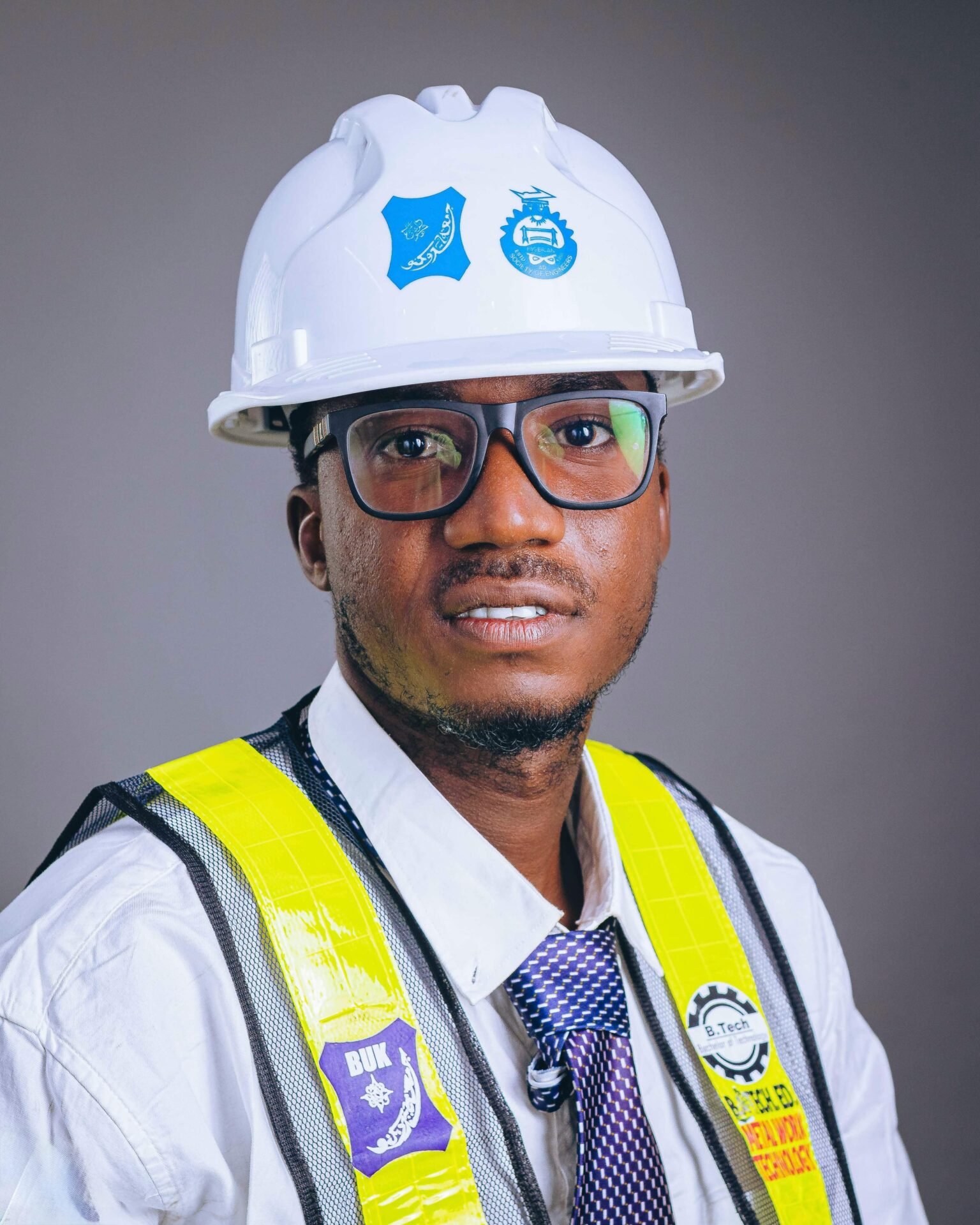 Professional African engineer wearing safety gear and helmet, posing confidently in studio.